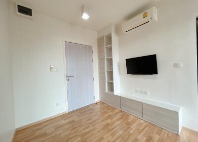 Living room with wooden floor, wall-mounted TV, air conditioner, and built-in shelves