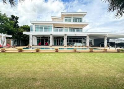 Exterior view of a modern multi-story house with pool and lawn