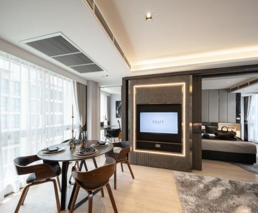 Modern living area with dining table, chairs, TV, and large windows