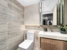 Modern bathroom with toilet, sink, and mirrored cabinet