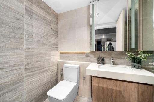 Modern bathroom with toilet, sink, and mirrored cabinet