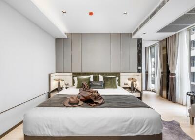 Modern bedroom with large bed, bedside tables, lamps, and luggage.