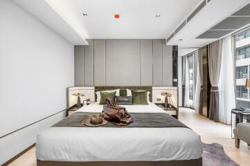 Modern bedroom with large bed, bedside tables, lamps, and luggage.