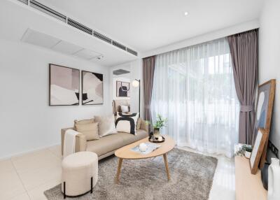 Modern living room with a cozy setup including a beige sofa, coffee table, and large window with draped curtains