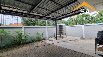 Covered outdoor area with metal roof, paved flooring, railing, and a water tank