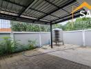 Covered outdoor area with metal roof, paved flooring, railing, and a water tank