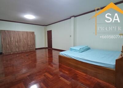 Spacious bedroom with wooden floor, bed, and wardrobe