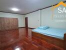 Spacious bedroom with wooden floor, bed, and wardrobe