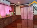 Spacious living room with wooden flooring and pink curtains