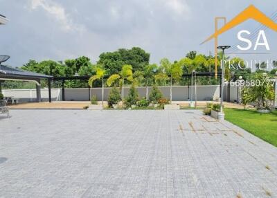 Spacious paved outdoor area with greenery and a modern building in the background