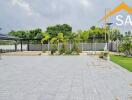 Spacious paved outdoor area with greenery and a modern building in the background