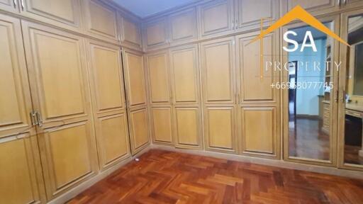 Spacious bedroom with ample wooden wardrobes and parquet flooring