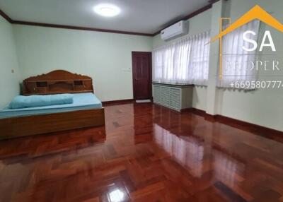 Spacious bedroom with wooden floor and air conditioning