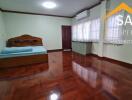 Spacious bedroom with wooden floor and air conditioning