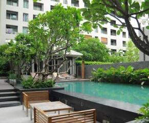 Outdoor pool area with greenery and nearby seating