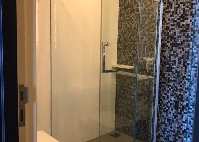 Modern bathroom with glass shower enclosure and mosaic tiled wall