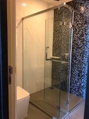 Modern bathroom with glass shower enclosure and mosaic tiled wall