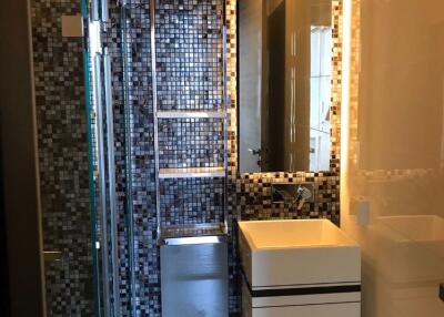 Modern bathroom with mosaic tile wall, glass shower door, and floating sink