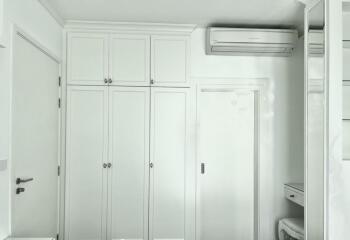 Bright white bedroom with built-in storage cabinets and air conditioning unit