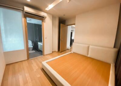 Spacious bedroom with wooden flooring and adjacent en-suite bathroom