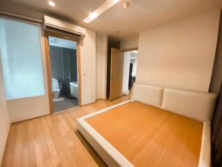 Spacious bedroom with wooden flooring and adjacent en-suite bathroom