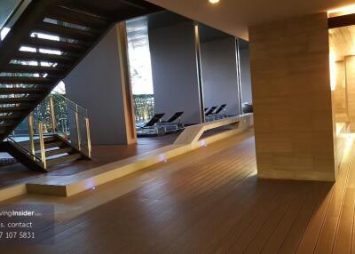 Modern building interior with wooden flooring and stairway, including poolside lounge area