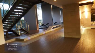 Modern building interior with wooden flooring and stairway, including poolside lounge area