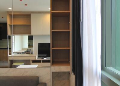 Modern living room with grey sofa, shelves, windows with curtains, and a mirrored wall