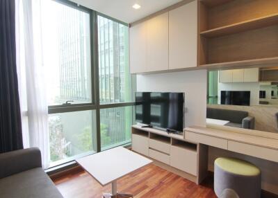 Modern living room with large windows, a flat-screen TV, and built-in shelves and drawers