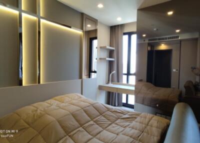 Modern bedroom with bed, large mirror, and ample lighting