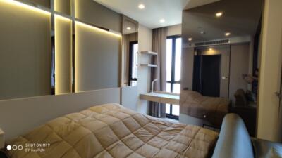 Modern bedroom with bed, large mirror, and ample lighting