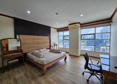 spacious bedroom with wooden furniture and large windows