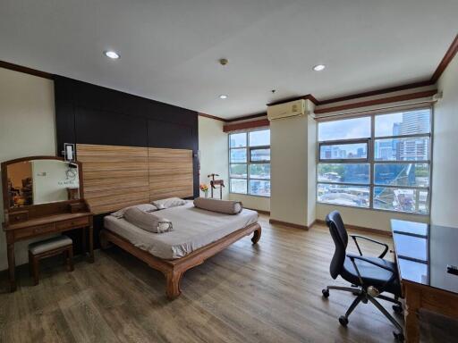 spacious bedroom with wooden furniture and large windows