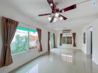 Spacious living room with large windows and ceiling fan