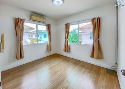 Spacious bedroom with wooden flooring and large windows