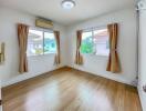 Spacious bedroom with wooden flooring and large windows