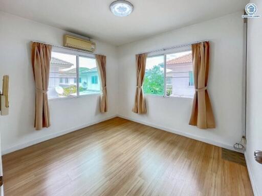 Spacious bedroom with wooden flooring and large windows