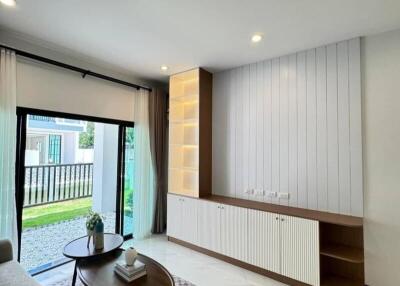 Modern living room with large sliding glass door, light-colored sofa, coffee table, built-in shelving unit, and ample natural light