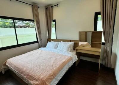 Bedroom with large windows, bed, and vanity desk