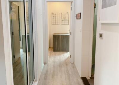 Bright hallway with light wooden floor leading to a room