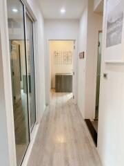 Bright hallway with light wooden floor leading to a room