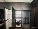 Modern storage and laundry area with built-in cabinets and washing machine.