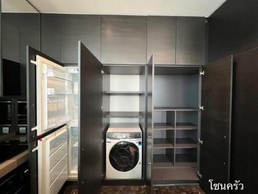 Modern storage and laundry area with built-in cabinets and washing machine.