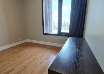 City view from a modern bedroom with wooden flooring and a dark wooden dresser