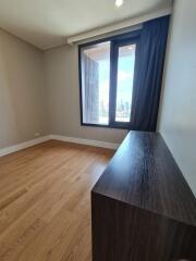 City view from a modern bedroom with wooden flooring and a dark wooden dresser