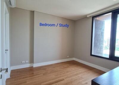 Spacious bedroom or study area with large window and wooden flooring