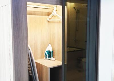 View of a closet with shelves, an iron, and an adjacent bathroom.