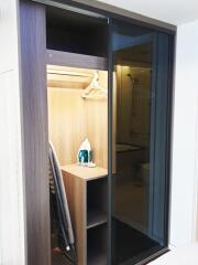 View of a closet with shelves, an iron, and an adjacent bathroom.