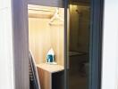 View of a closet with shelves, an iron, and an adjacent bathroom.