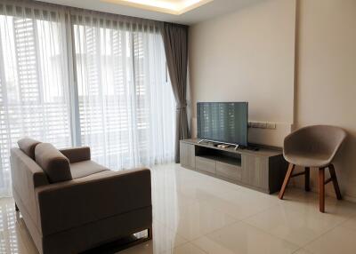 Modern living room with large windows, sofa, TV, and chair